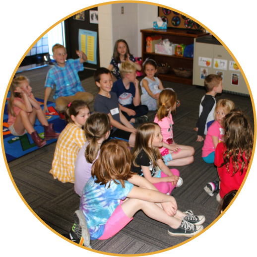 young kids sitting on carpet in classroom