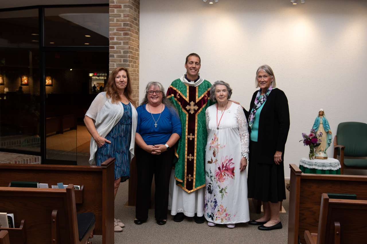 four women posing for a picture with a priest