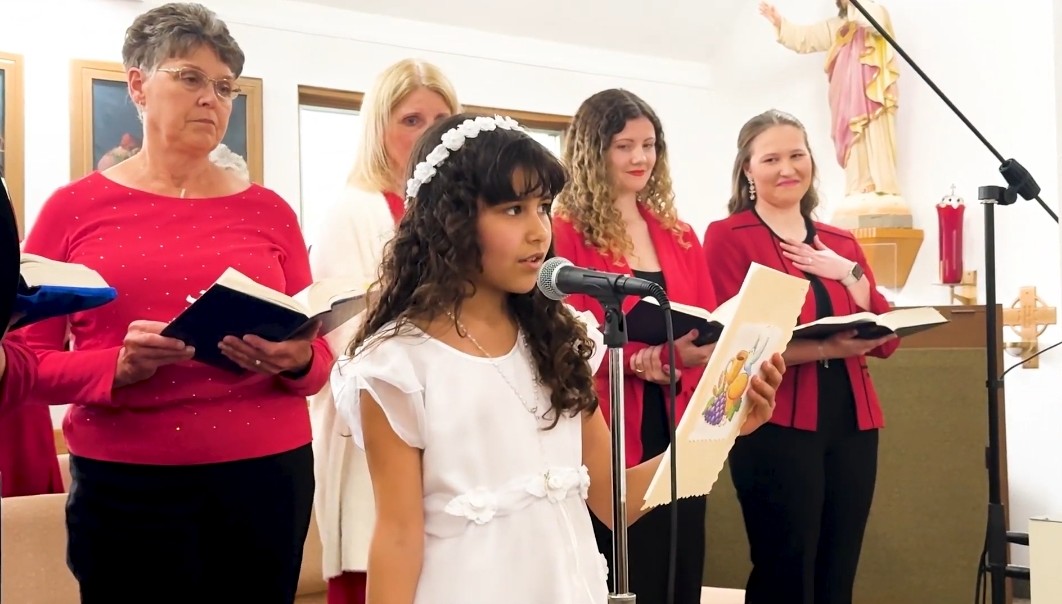 little girl in her first communion dress singing with 4 women singing behind her