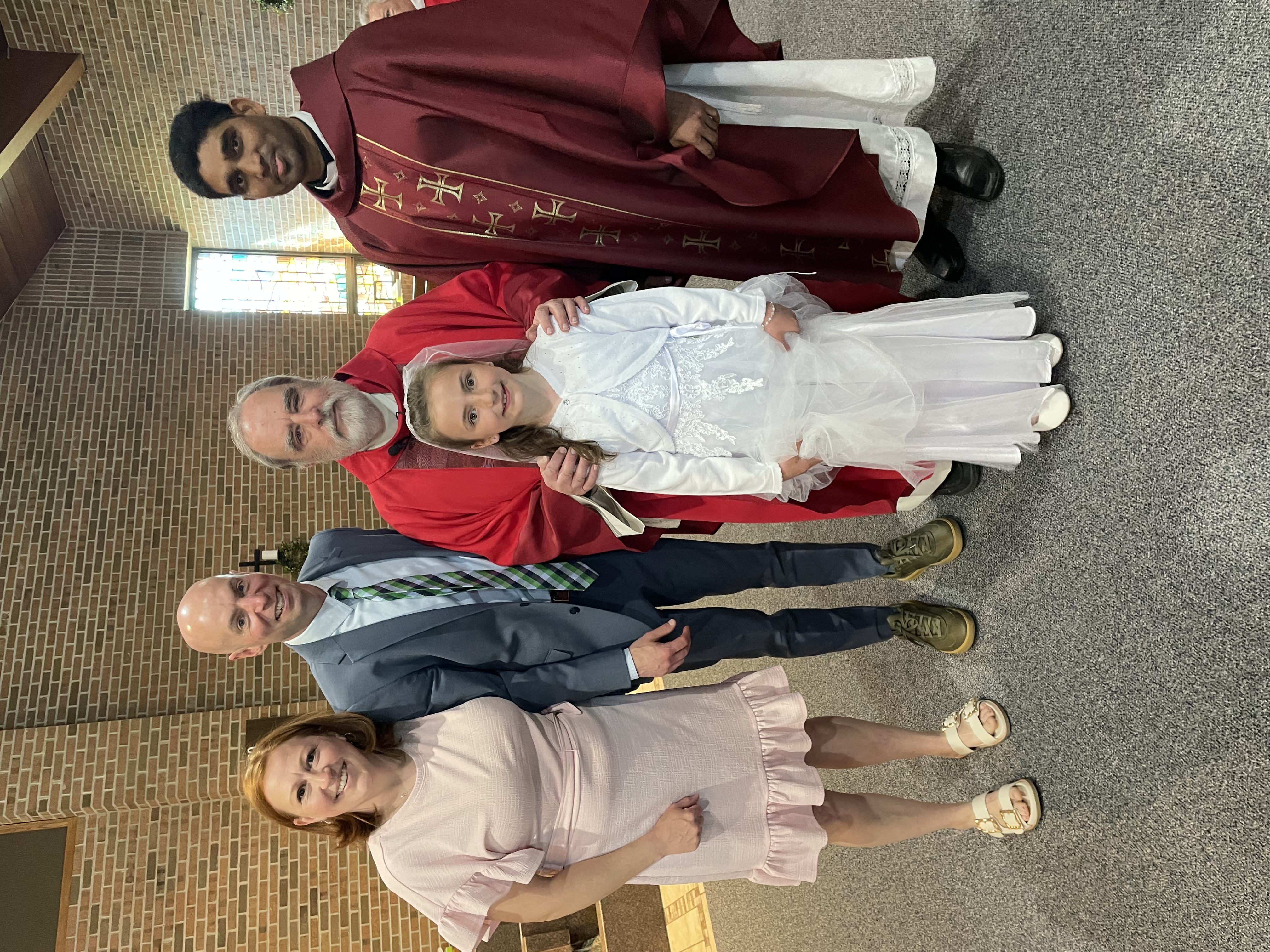 little girl with her parents and priests after her First Communion