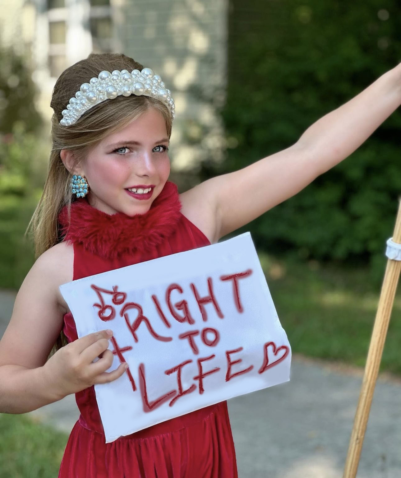 little girl in red dress holding paper sign