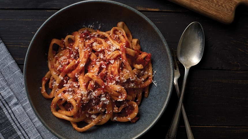 pasta amatriciana in plate with spoon and fork