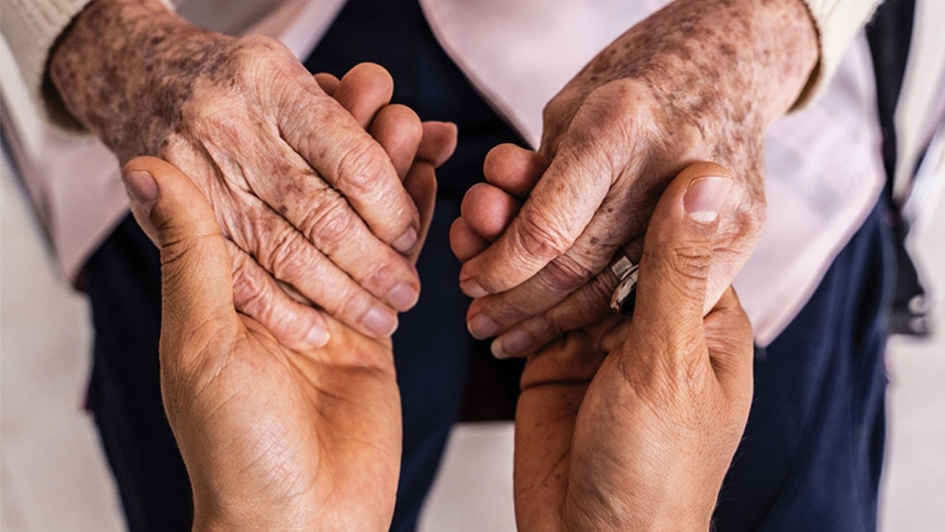 elderly person and younger person holding hands