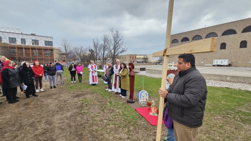 man holding cross with parishioners outside