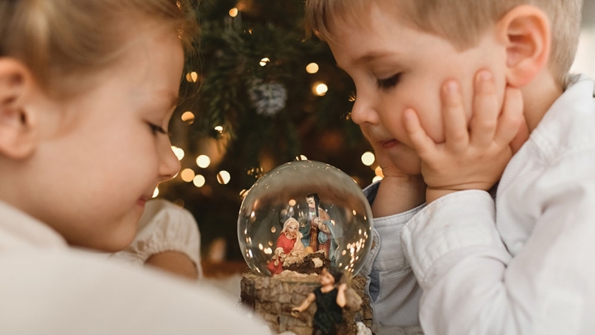young children looking at a snow globe of the Holy Family