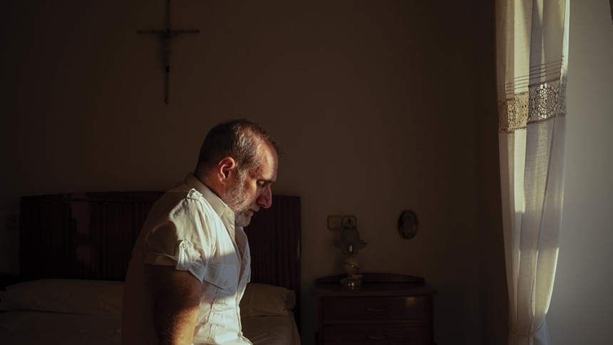 man sitting on bed and praying
