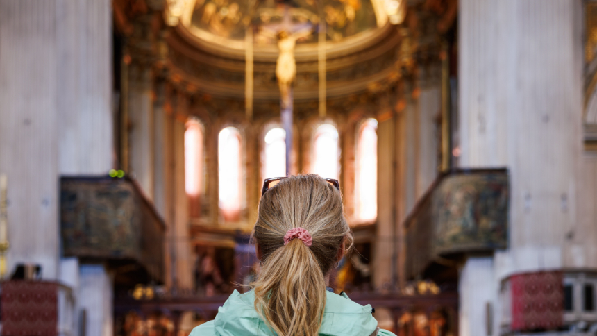 A woman stares at a crucifix in a chapel.