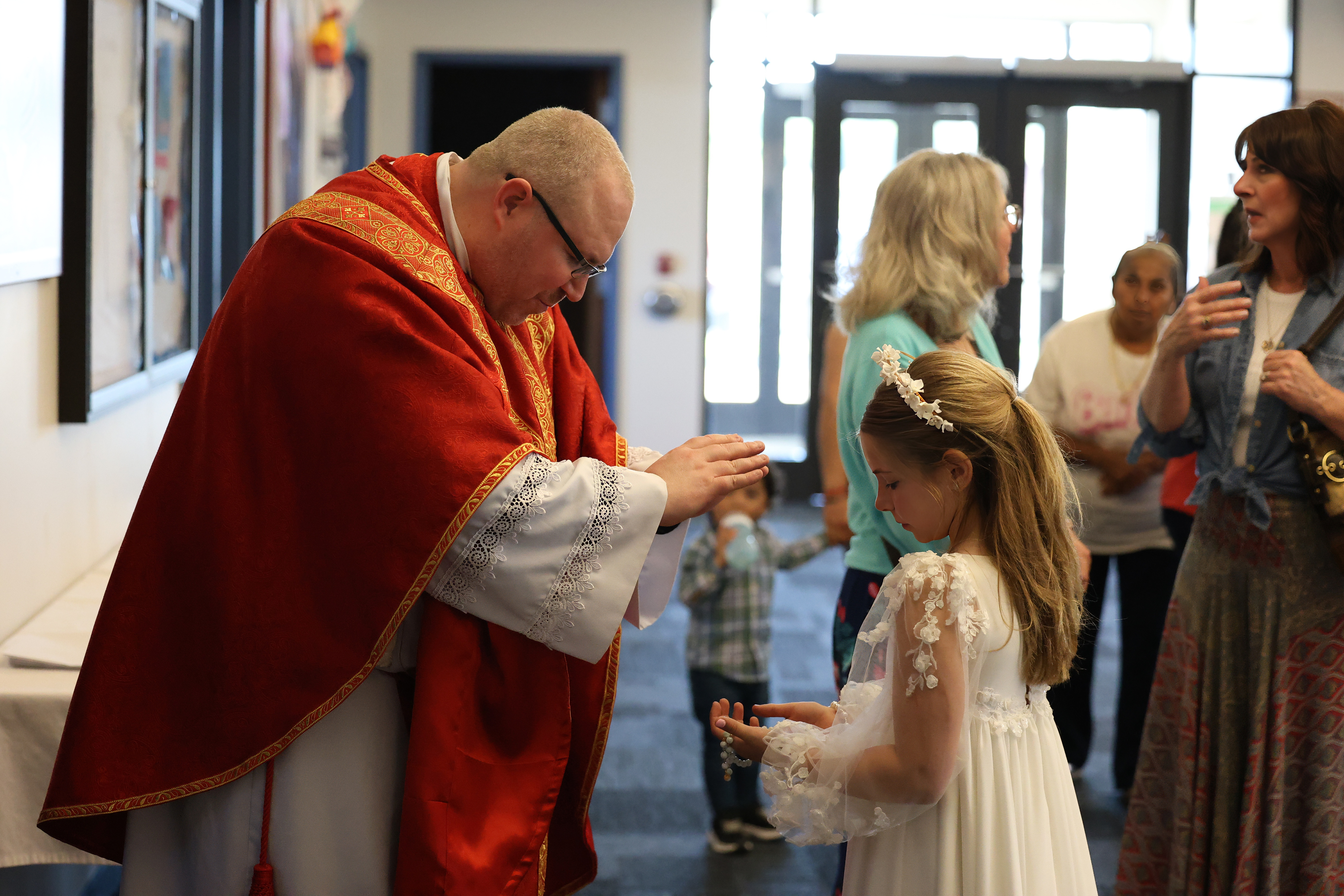 Priest blessing little girl's rosary