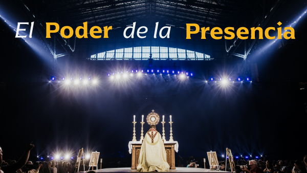 priest placing monstrance on an altar inside a darkened stadium
