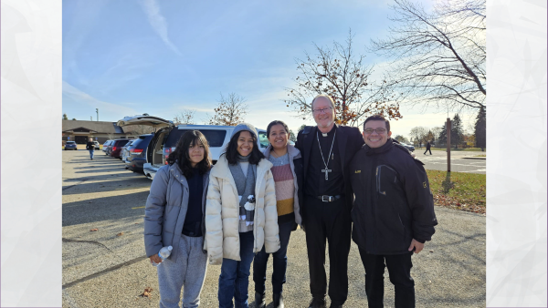 Hazzel, Bishop Walsh and her family standing in a parking lot