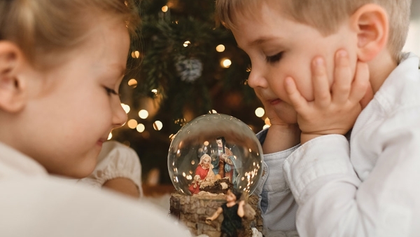 young children looking at a snow globe of the Holy Family